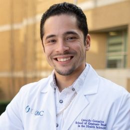 Male physiology student smiles while posing in front of Guyton research building.